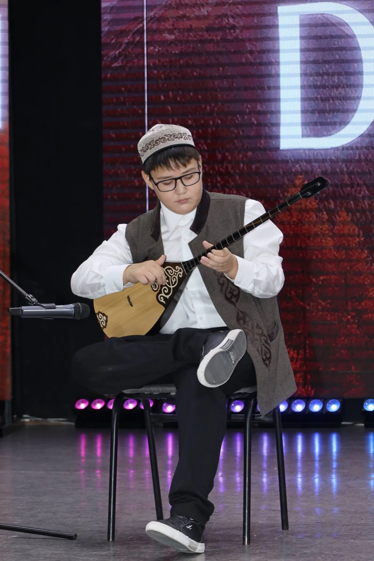 Юный домбрист выступает на сцене